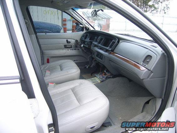 Interior of a 2003 Ford Crown Victoria showing light grey leather seats and dashboard