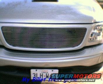Silver pickup truck grille with horizontal bars. License plate visible