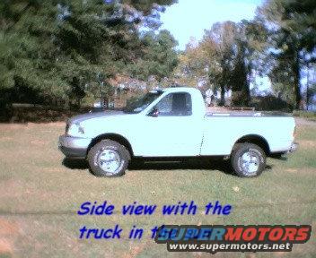 Side view of a 2000 Ford F-150 pickup truck parked on grass with trees in the background