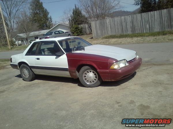 1987 Ford Mustang coupe with red front end and white rear body panels. Hood is unpainted