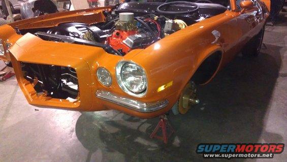 Orange 1973 Chevrolet Camaro front 3/4 view, engine exposed, on jack stands