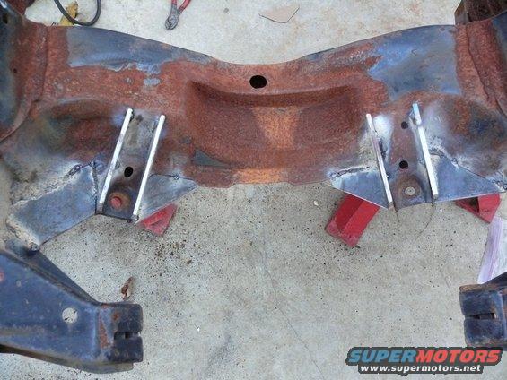rusted frame section with added metal plates, on red jack stands