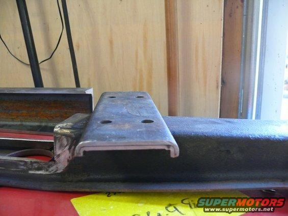 Metal bracket with four bolt holes, held in a vise