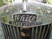 1991 Ford Bronco - Close-up of a White Super Power emblem on an old vehicle's front grille.