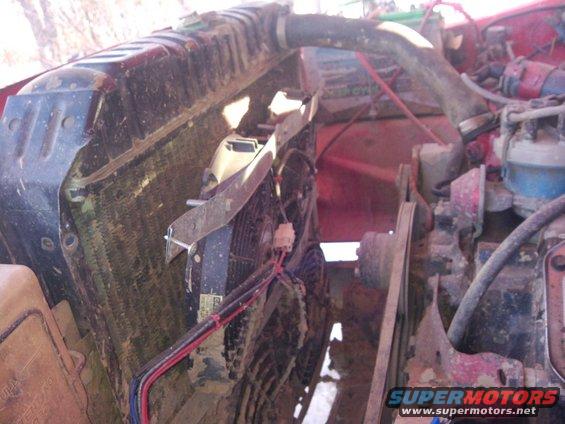 Engine bay showing radiator, fan, and belts. Some mud on parts