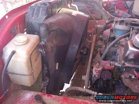 Red engine bay with black fan shroud, white coolant reservoir, and engine components visible