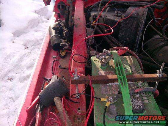 Engine bay with battery, tools, and wiring