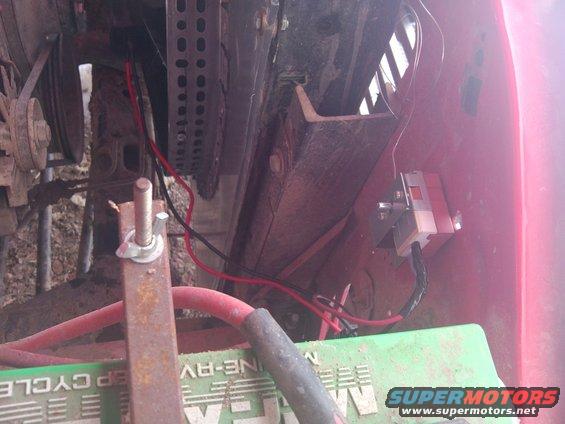 Close-up of engine bay wiring, battery, and some metal brackets