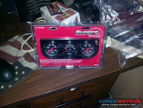Triple gauge kit in plastic packaging, showing oil pressure, voltage, and water temperature gauges