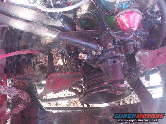 Engine component with pulley and hoses, showing rust and wear