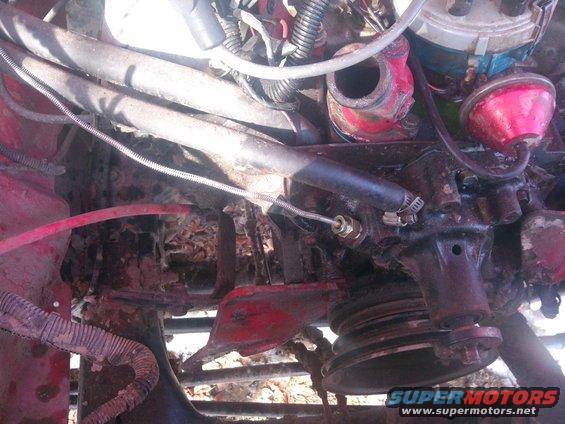 Engine bay with red paint, hoses, and a pulley system. Some debris is visible