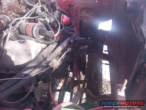 Engine bay with red paint, wires, and engine parts visible. Radiator is also partially seen