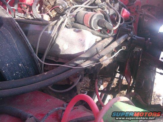 Engine bay with red paint, hoses, and wiring. A Supermotors logo is visible in the lower right
