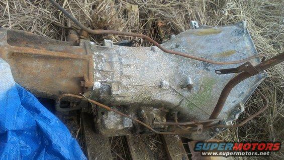 Old automatic transmission, looks rusty and dirty, sitting on the ground
