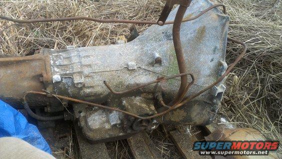 Transmission part, weathered aluminum casing, rusty metal lines, on dry grass