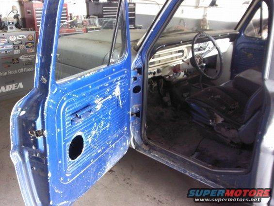 Blue pickup truck cab with door open, showing worn seat and dashboard