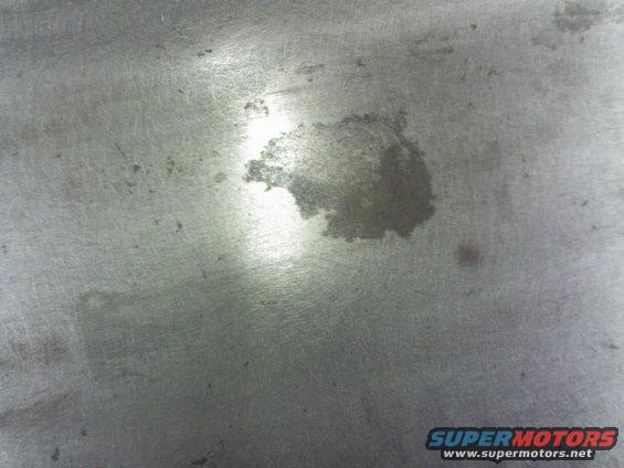 Metal surface with oil stain and Supermotors.net watermark