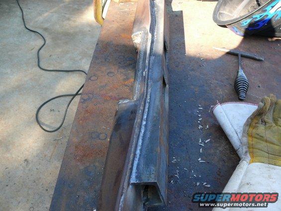 metal part on workbench with welding helmet and gloves nearby