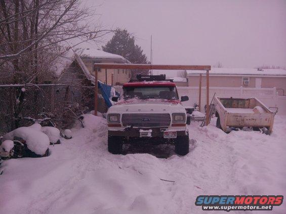1978 Ford Bronco with roof rack driving in snow, other vehicles visible