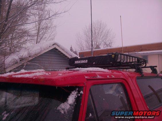 Red vehicle roof rack with dark crossbars, partially visible against a hazy sky