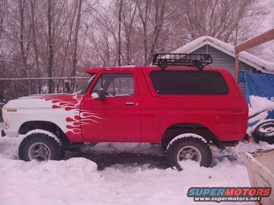 Red SUV with a roof rack parked in the snow, front fender is white