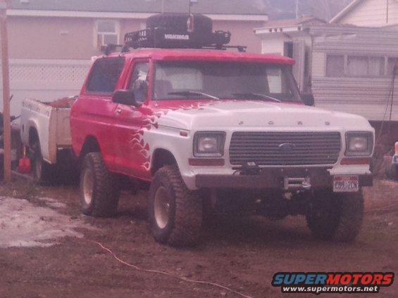 Red and white pickup truck with roof rack, front view