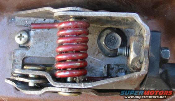 Close-up of a vehicle's door latch mechanism with a red spring and a bolt marked 8.8