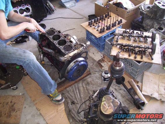 engine block, cylinder head, camshafts, and axles laid out on garage floor