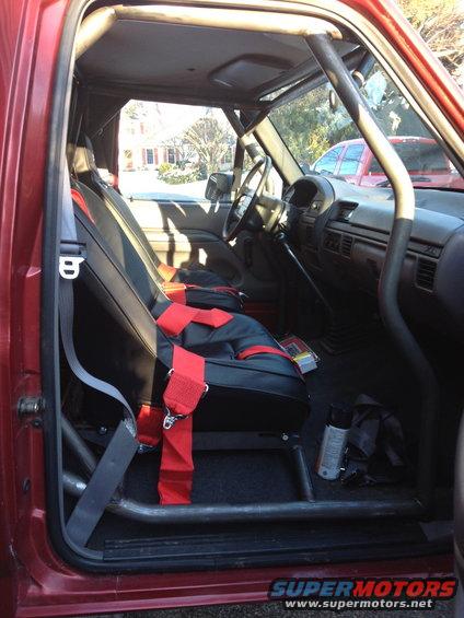 Interior of a red 1996 Ford F-150 with roll cage and racing seats