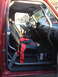 1996 Ford F-150 - The interior of a red 1996 Ford F-150 shows a custom roll cage and racing seats with red harnesses.