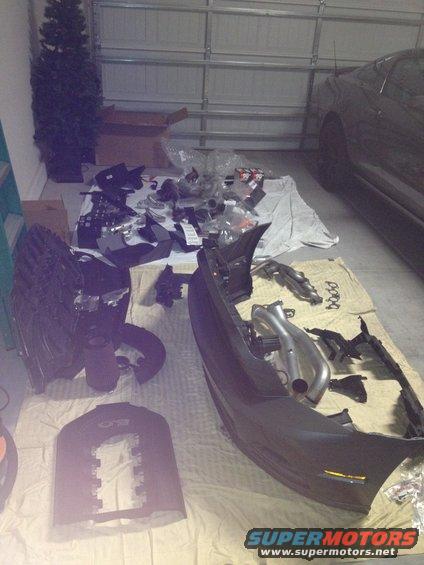Dark gray car parked in garage with disassembled parts on the floor