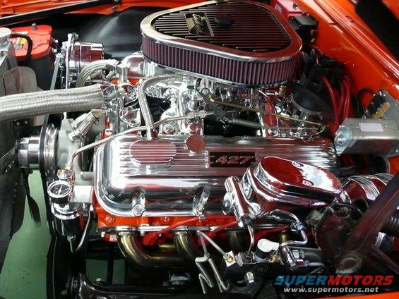 Close-up of a shiny V8 engine with a "427" emblem on the valve cover and an aftermarket air filter
