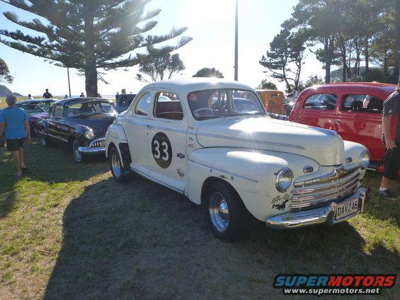 Cream 1946 Ford coupe with black circle and number 33 on door, racing decals, and license plate DAV246