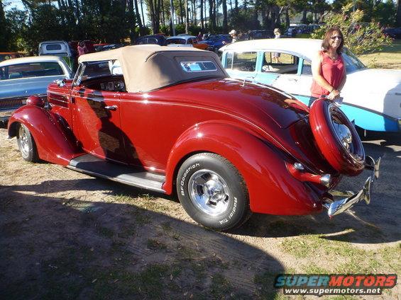 Red convertible with tan top and spare tire on rear bumper, parked next to a blue and white sedan