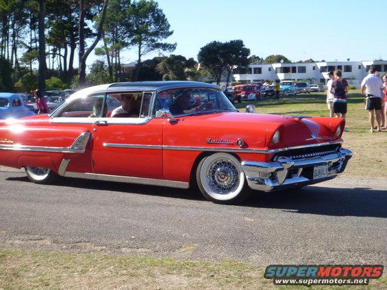 Red coupe with white roof and wide whitewall tires, chrome trim, and wire wheels. License plate reads 'SUNIVLY'