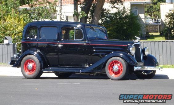 Black sedan with red wheels parked on street. License plate reads "4 CUBES"