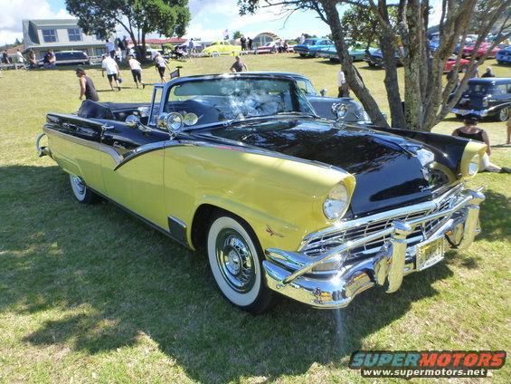 Yellow and black convertible parked on grass with people in background