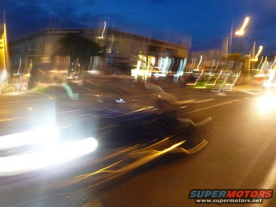 Dark car with blurred lights on a street at dusk