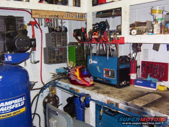 Workshop with air compressor, welding equipment, tools, and storage bins