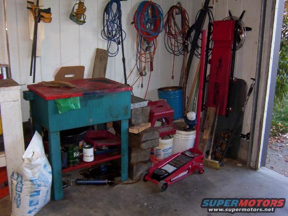 Garage interior with workbench, tools, and a red floor jack