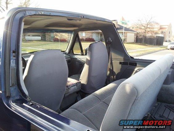 Interior of a blue 1995 Ford Bronco with top removed, showing front and rear seats
