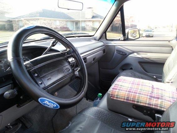 Interior of a 1990s Ford truck, showing steering wheel with Ford logo, dashboard, and plaid-covered center console