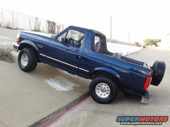 Blue 1995 Ford Bronco convertible SUV, side view with spare tire mounted at rear