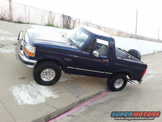 Dark blue Ford Bronco parked on a concrete incline, spare tire mounted on the back