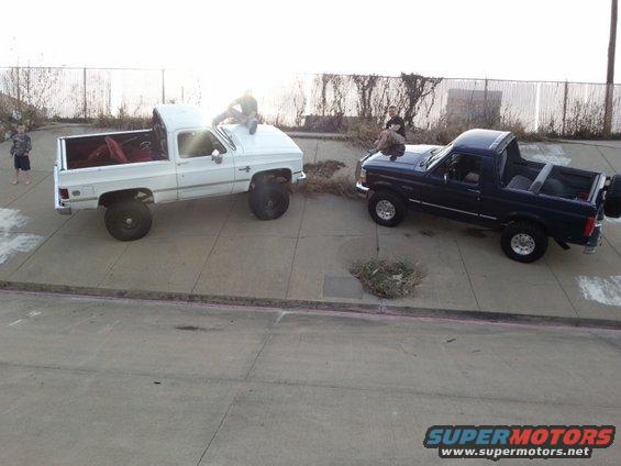 Dark blue 1995 Ford Bronco with removable top, parked next to a white pickup truck