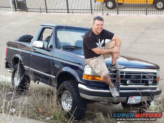 1995 Ford Bronco with a man sitting on the hood. License plate BY3 5006
