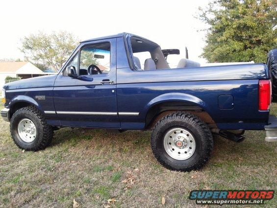 Blue Ford Bronco convertible side view with chrome trim and off-road tires