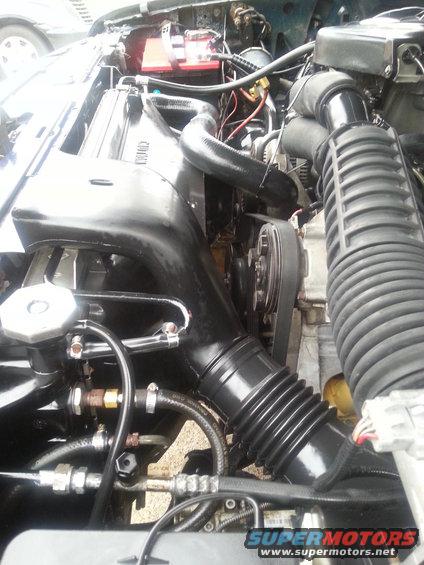 1995 Ford Bronco engine bay with black intake hoses, radiator, and battery
