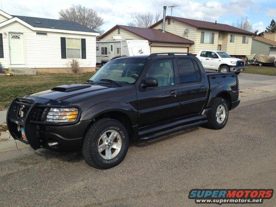 Dark 2005 Ford Sport Trac parked in a driveway with a white truck behind it
