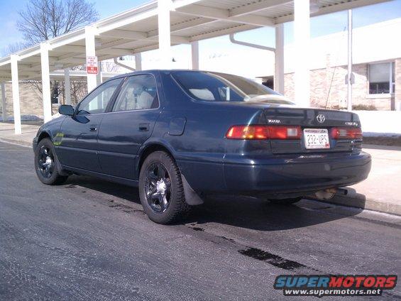 Dark blue sedan parked on asphalt, rear quarter view. License plate reads 232-UPS